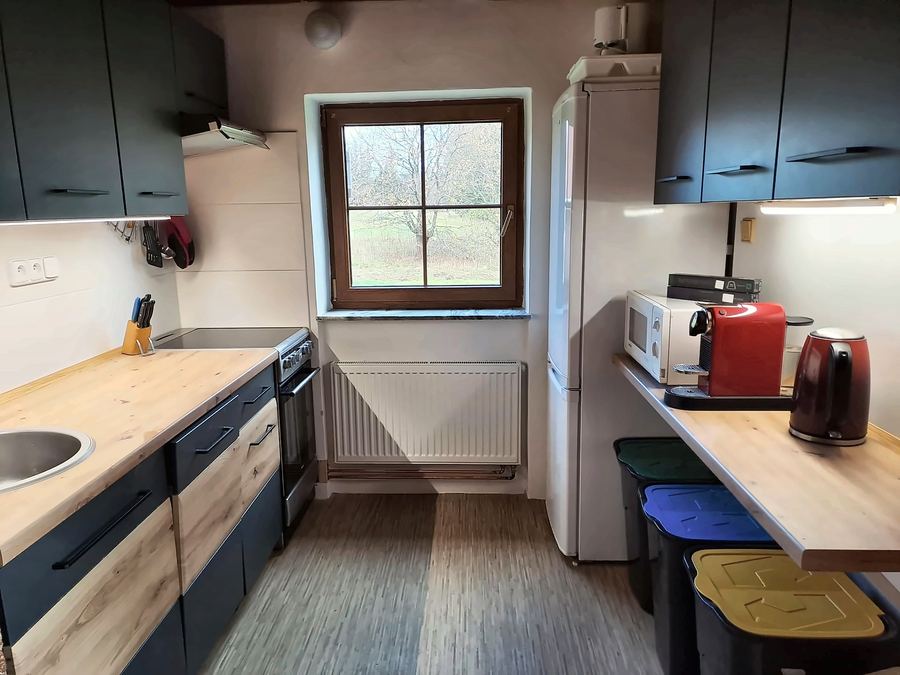 Kuchyňská linka s dřevěnou deskou pod oknem, varné konvice a kávovar