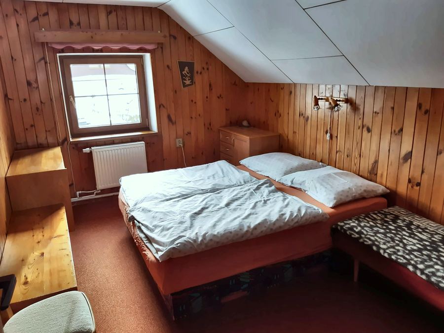 Ložnice s manželskou postelí pod šikmým stropem
